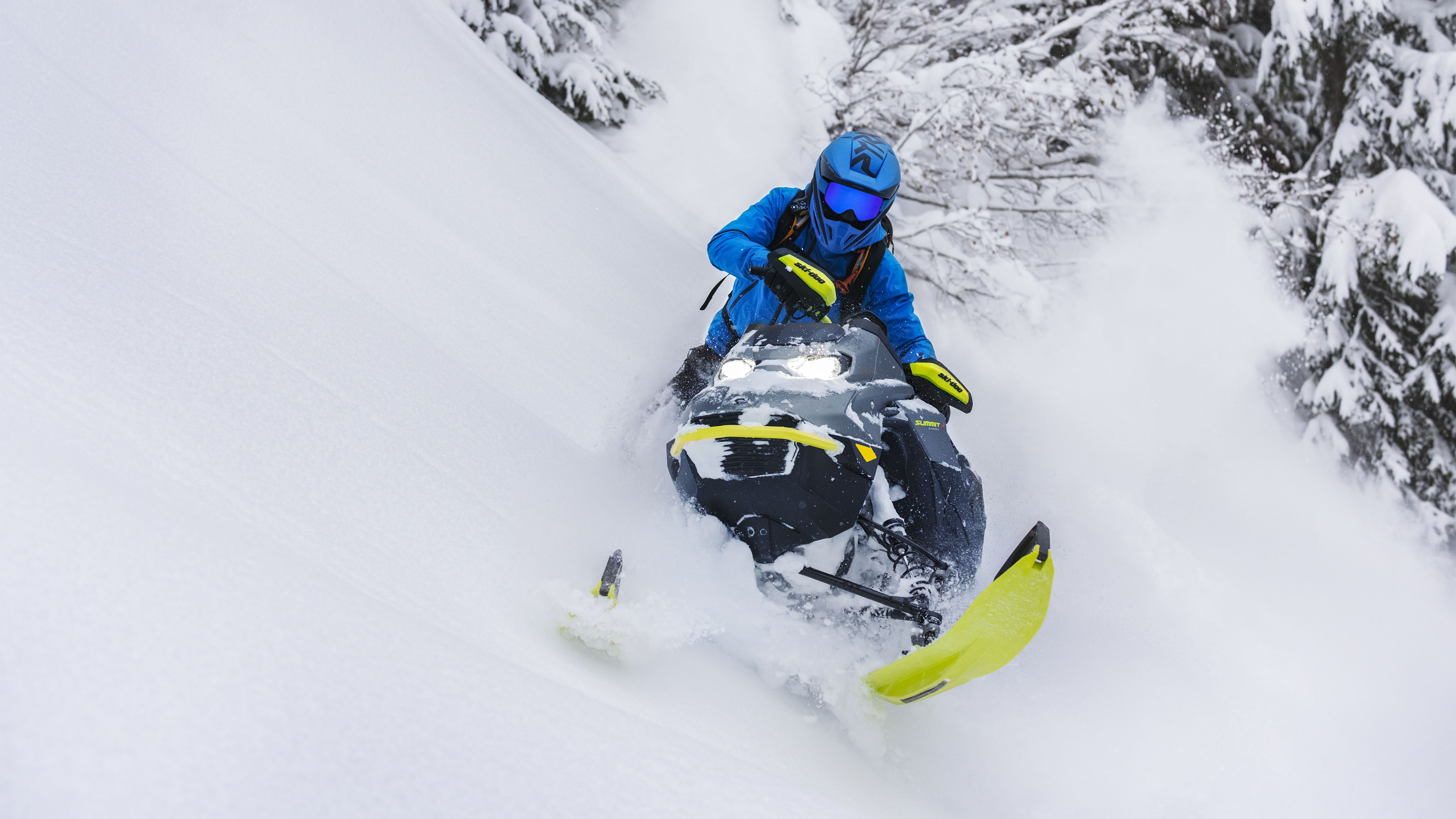 Jazdec na snežnom skútri v zákrute v hlbokom snehu na skútri Ski-Doo Summit model 2023