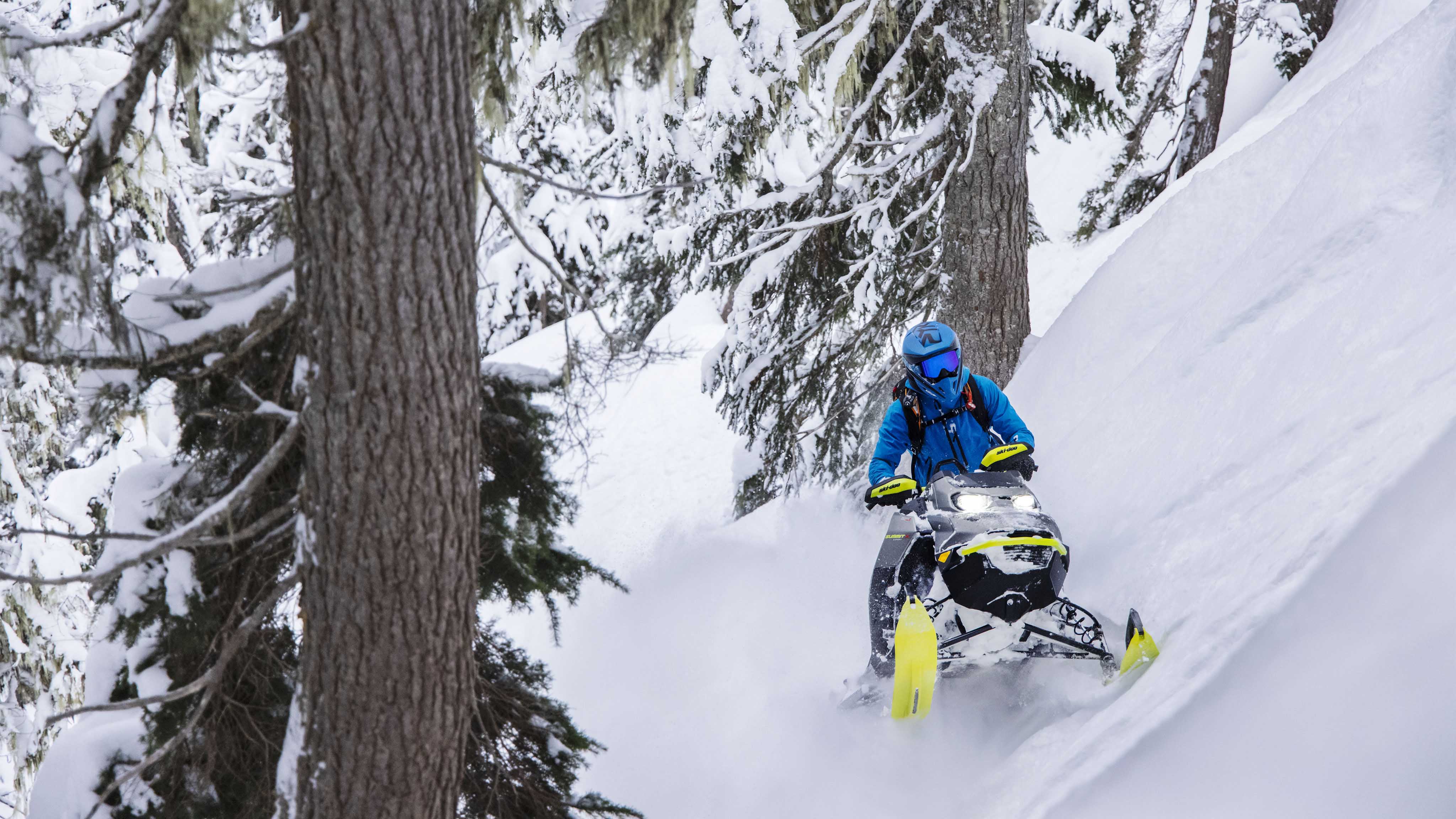 Момче кое ја вози својата Ski-Doo Summit 2023 моторна санка во длабочините на шумските падини