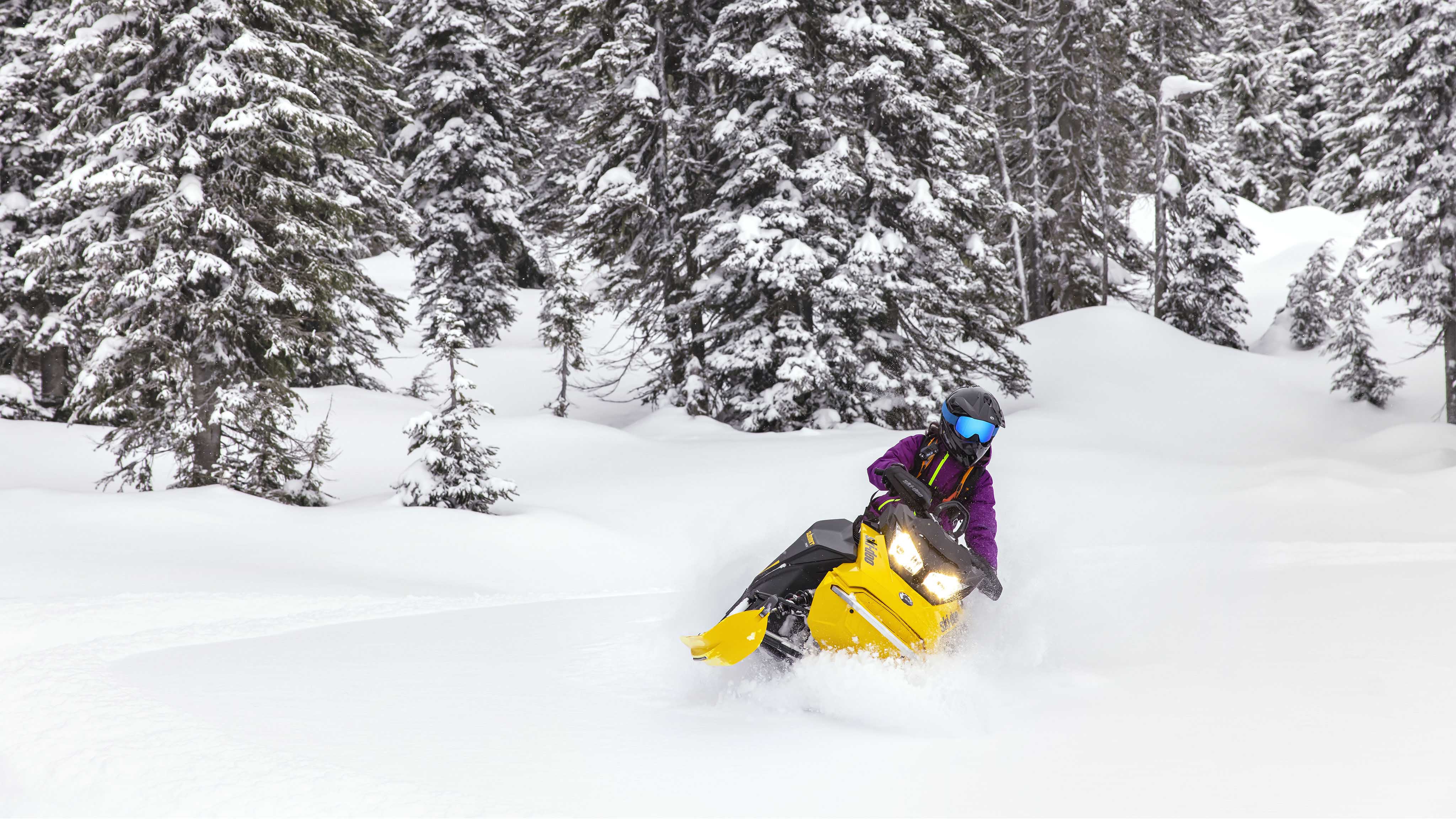 Kobieta ciesząca się jazdą w głębokim śniegu dzięki skuterowi śnieżnemu Ski-Doo Summit Neo