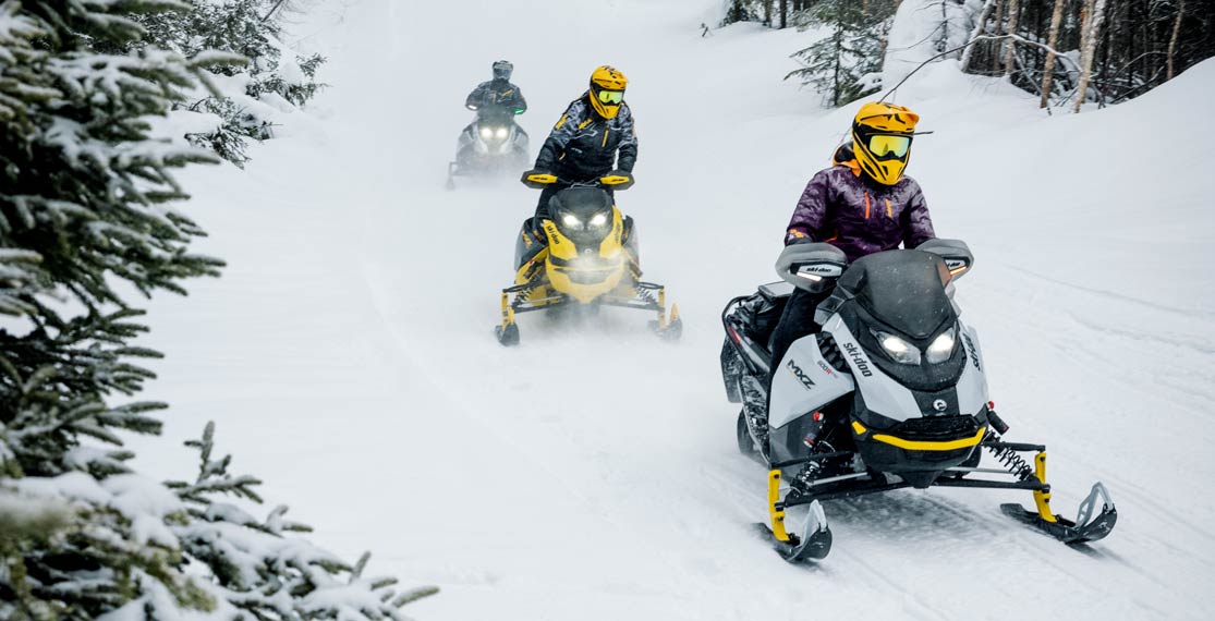 group of people riding Ski-Doo snowmobiles